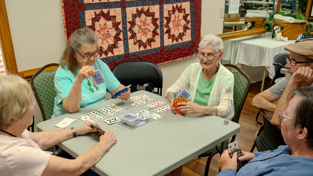 Active seniors smiling and playing card games together at Heritage Place Senior Center