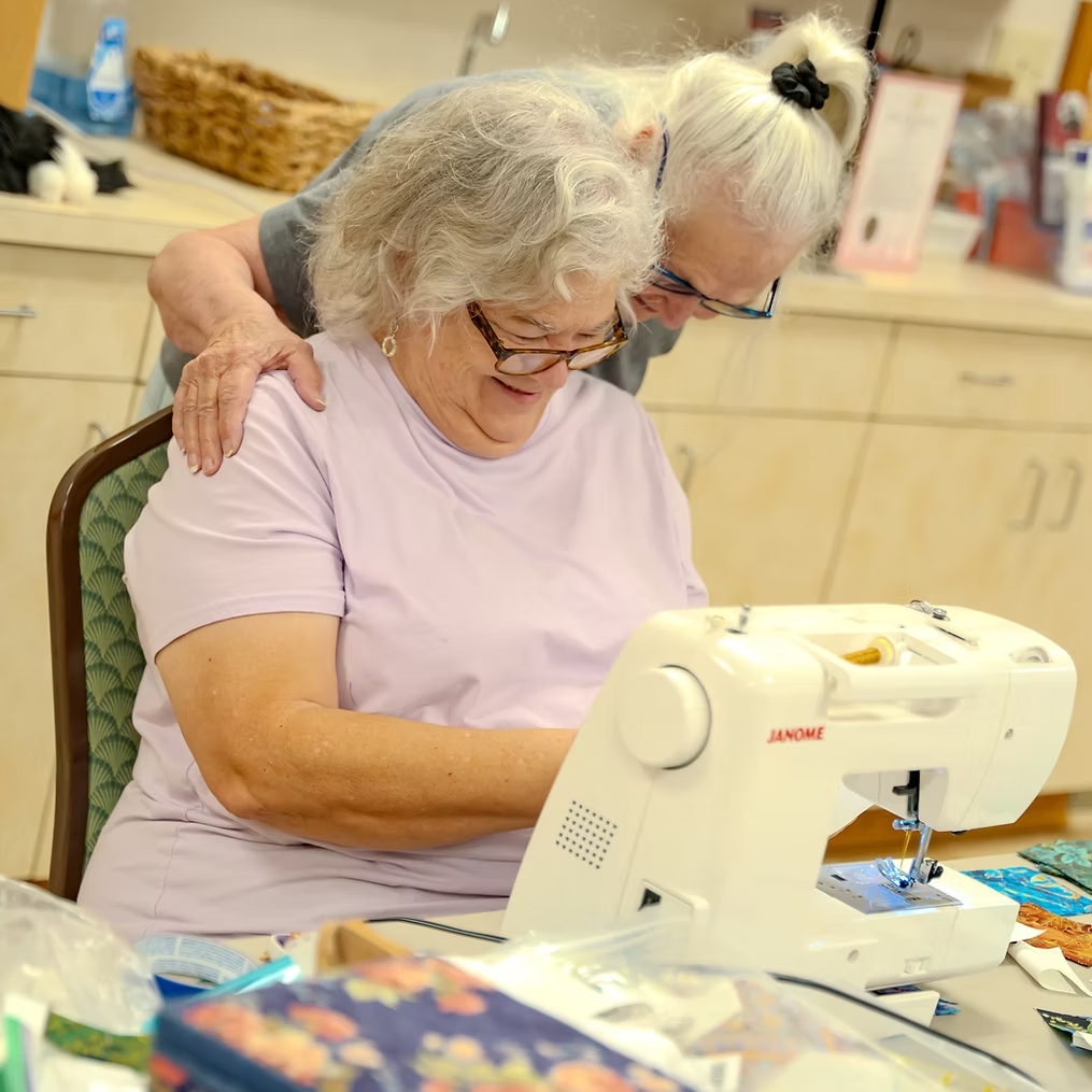 Two women sharing a warm moment at a sewing machine